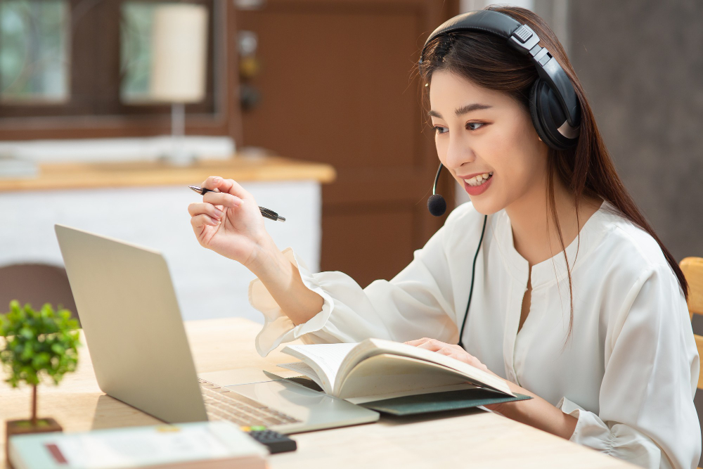smiling asian young female using headset looking laptop screen listen learning online courses - Video-powered Learning with Maketric